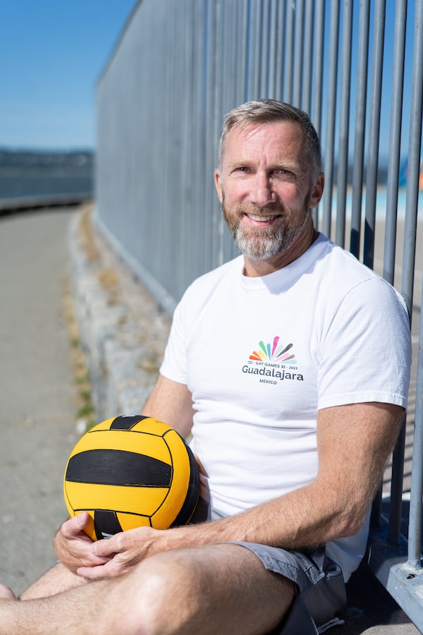Sean Fitzgerald, co-president of the Federation of Gay Games, sits outside Second Beach Pool in Vancouver, B.C. on Monday, June 5, 2023 as he holds a ball used for water polo. Fitzgerald competes in water polo and swimming at the Gay Games.