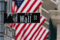 The American flag flies behind a Wall Street sign near the New York Stock Exchange (NYSE) in New York City on April 22, 2026. (Photo by ANGELA WEISS / AFP via Getty Images)