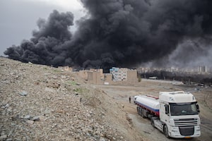 Plumes of smoke rise over oil depot tanks hit by joint Israel-U.S. strikes overnight near Tehran.