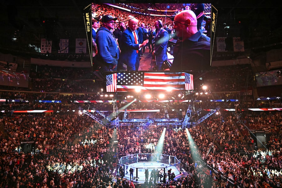 The big screen at the Prudential Center in Newark, N.J., displays U.S. President Donald Trump reaching out to shake hands with Joe Rogan as he attends the UFC 316 event on June 7.