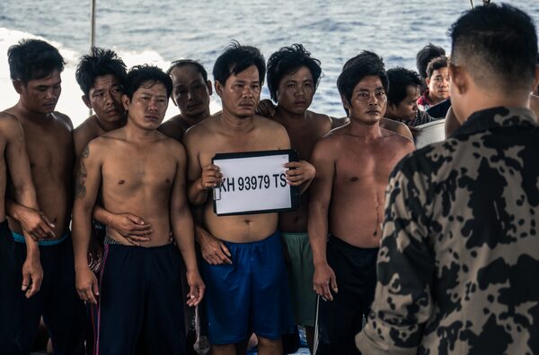 Arrested crew from a Vietnamese fishing boat are photographed and booked.